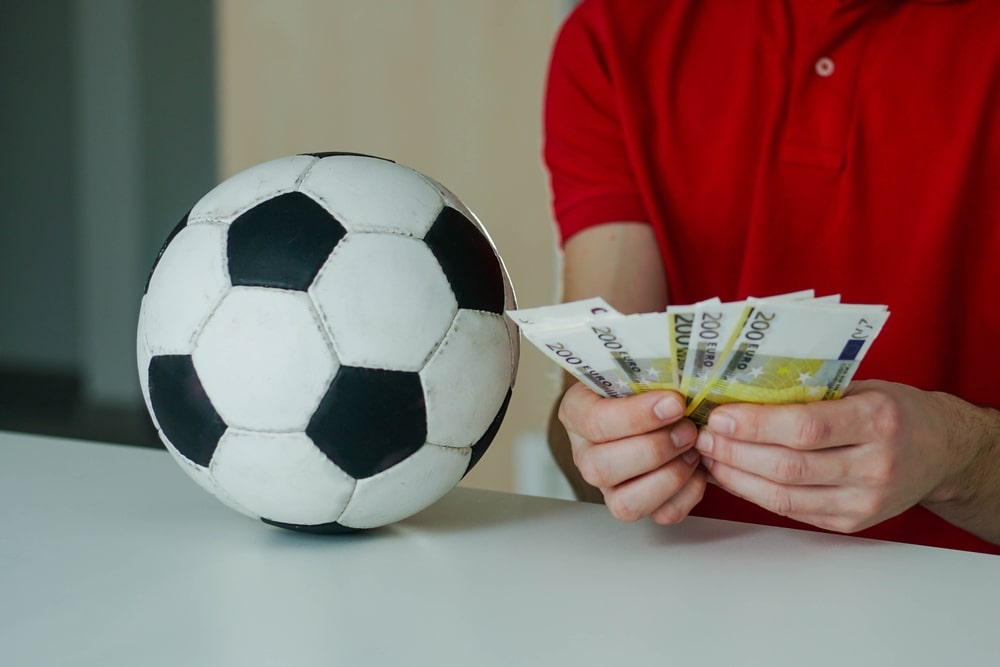 football with hand with money next to it