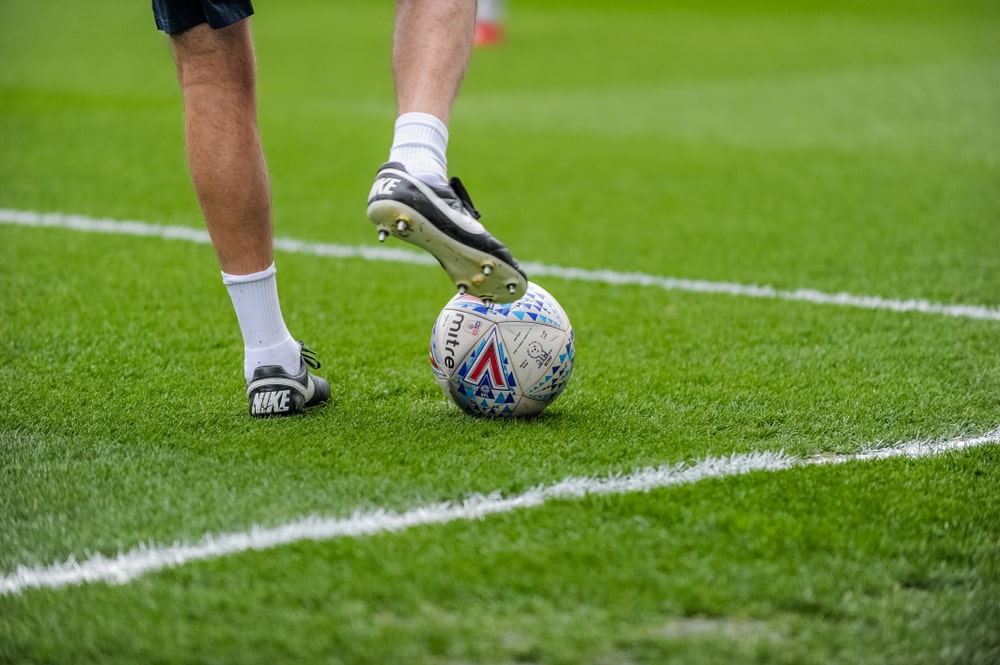 Footballer's legs with a ball on stadium